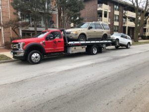 a-flatbed-tow-truck-towing-a-car-down-a-street.