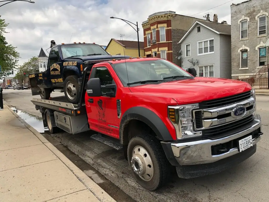 A junk car on the flatbed of a truck from A+ Junk and Tow on the street of Bolingbrook iL | Selling Junk Car in Bolingbrook