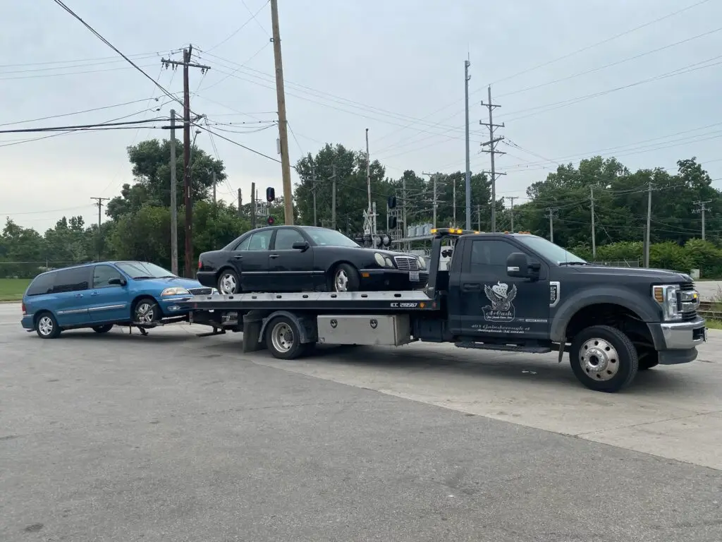 A junk car on the flatbed of a truck from A+ Junk and Tow on the street of Bolingbrook iL