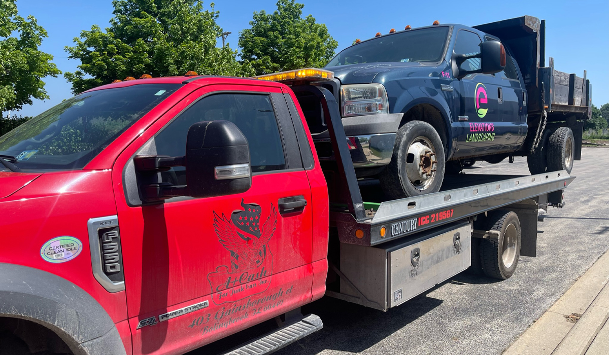 junk vehicle being towed away by a large red truck