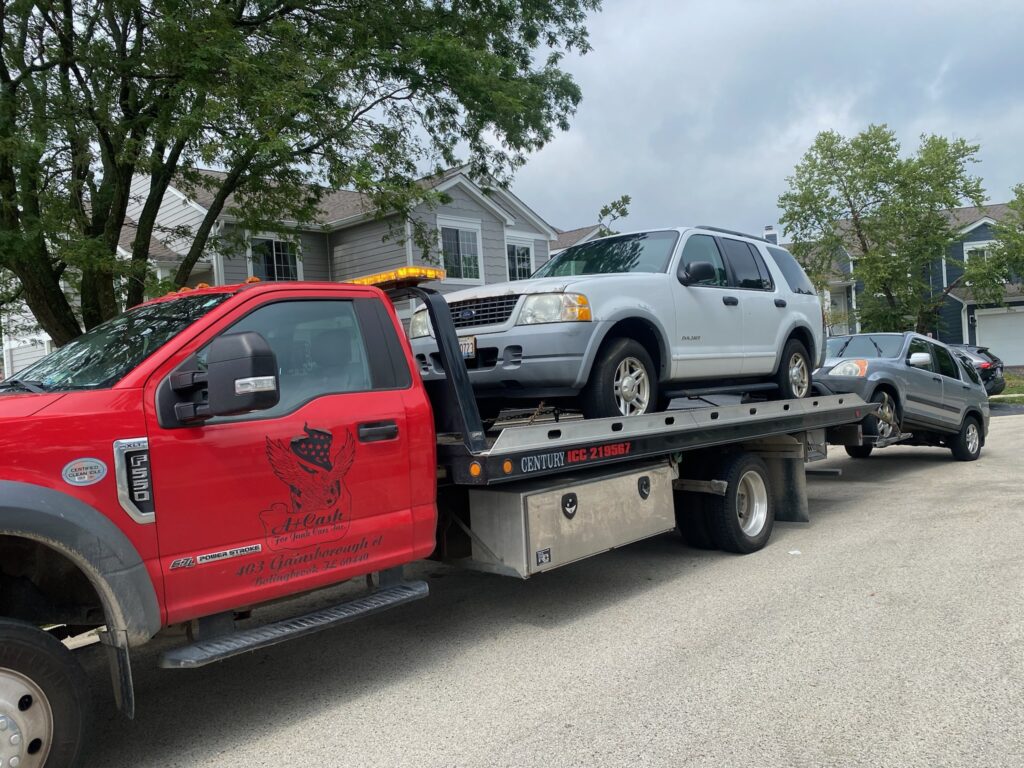 Tow truck on the street towing away a white junk car