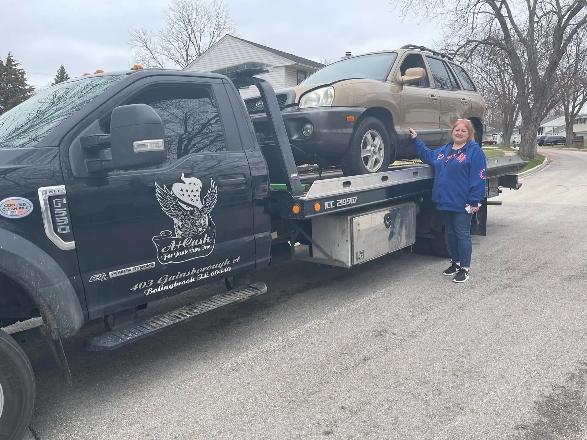 Tow truck hauling away a Flood-Damaged Car in Joliet, with woman seller standing beside vehicle during sale.
