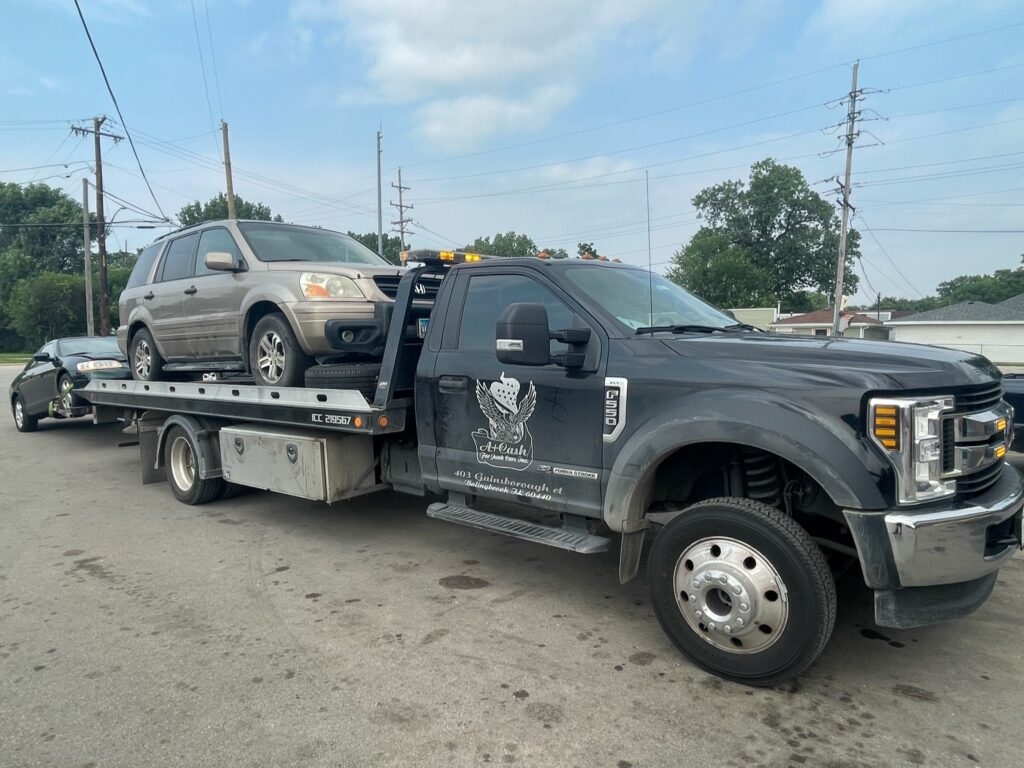 Tow truck on the street towing away a gray junk car