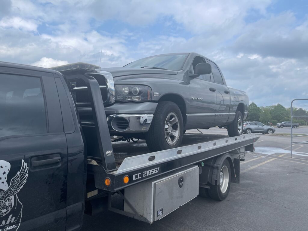 A junk car on the flatbed of a truck from A+ Junk and Tow on the street of Romeoville IL