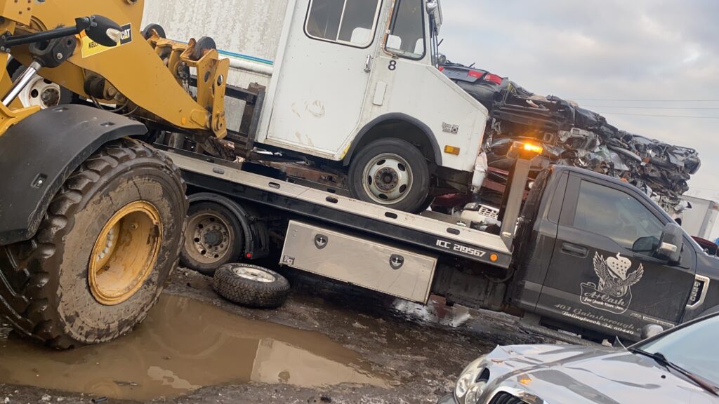 A junk car on the flatbed of a truck from A+ Junk and Tow on the street of Romeoville IL