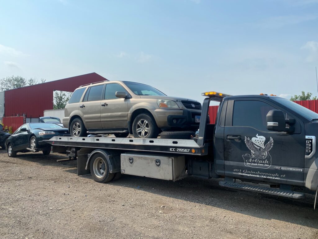 A junk car on the flatbed of a truck from A+ Junk and Tow on the street of Western Springs IL