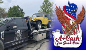 a yellow junk car getting towed by a black towing truck