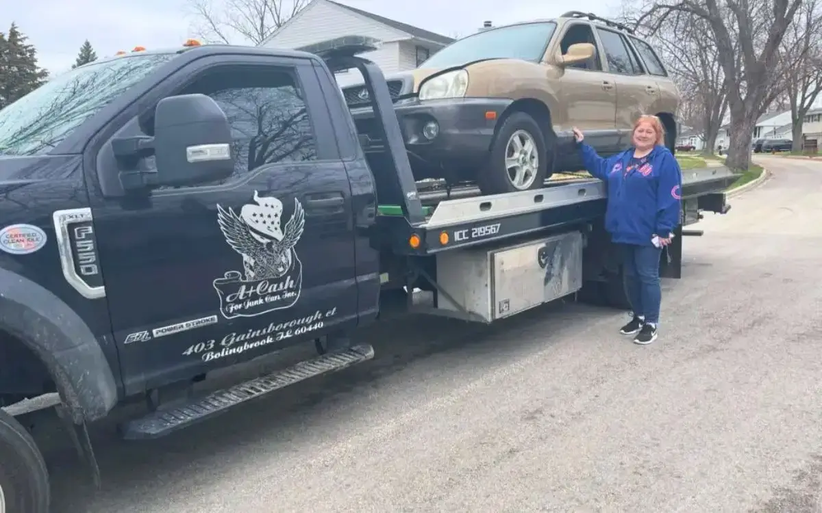 A woman stands next to a Junk Car Removal truck in Burr Ridge, IL, loading a beige SUV, showcasing A+ Cash For Junk Cars services.