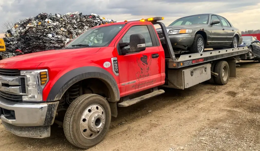 Red tow truck transporting an old car for scrap, highlighting the importance of assessing junk car value.