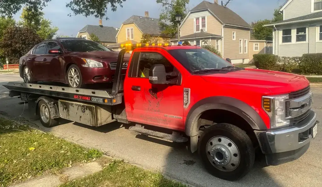 Red tow truck transporting a sedan, demonstrating services to turn your old car into cash quickly in Homer Glen, IL.