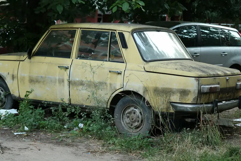 A old car in a junk waiting to be tow by a professional car disposal service