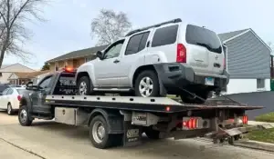 Flatbed tow truck hauling broken-down SUV, showing vehicle removal service after car breaks down in neighborhood.