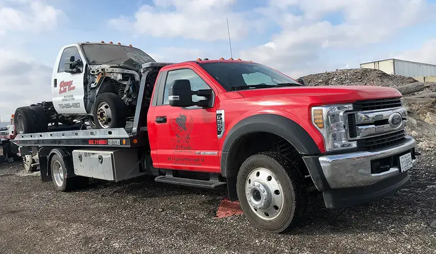 Tow truck transporting severely damaged wrecked vehicle to salvage yard, showing fast cash solutions for unusable cars.