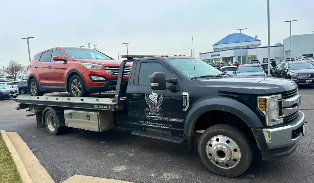 Flatbed truck towing a high-mileage car from dealership for junk car removal in Crest Hill, Illinois.