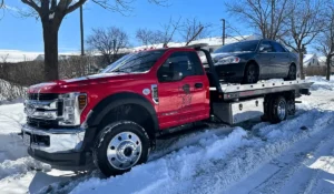 Tow truck transporting a snow-covered sedan in Homer Glen during winter, showing what it looks like to junk that old vehicle before cold weather worsens damage.